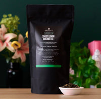 Back of the Superbloom tea pouch beside a small bowl of loose tea, with flowers behind